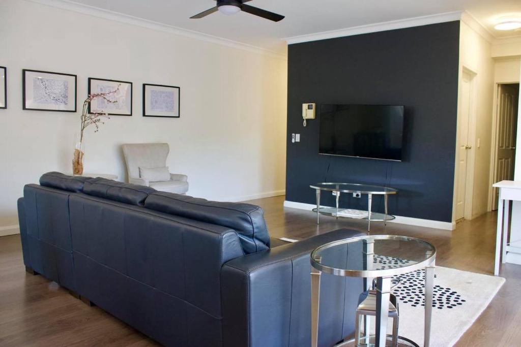 悉尼Home away from Home Parramatta的客厅配有蓝色的沙发和电视