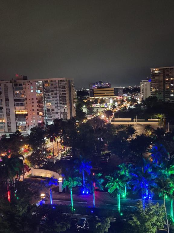 圣胡安Beautiful remodeled condominiun with an impecable view to the beach and city avenues walk distance to the beach的夜晚的城市,有蓝色和绿色的灯光