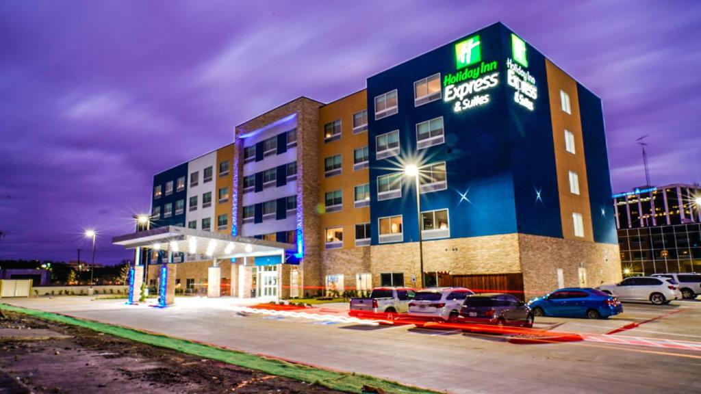 达拉斯Holiday Inn Express & Suites - Dallas Market Center, an IHG Hotel的停车场内有车辆的旅馆