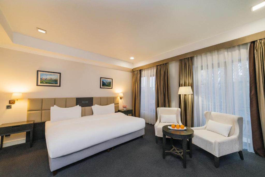 比什凯克大史酒店的卧室配有一张白色大床和一把椅子