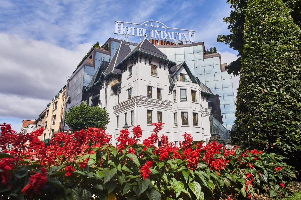 毕尔巴鄂因多图西尔肯酒店的一座白色的建筑,在一座建筑前方,有红色的花朵