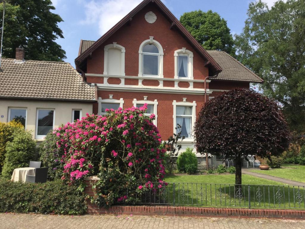 奥尔登堡Ferienhaus Us lütt Hus und das Zimmer Linde im Haupthaus的前面有粉红色花的房子
