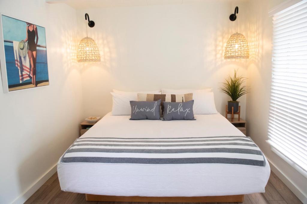 韦尔弗利特Endless Coast, A Boutique Hotel的卧室配有一张带两个灯的大白色床