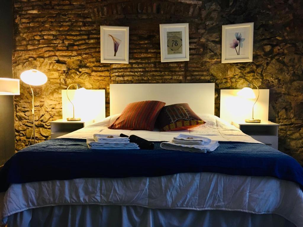科洛尼亚-德尔萨克拉门托Estudio Taller de Tejas Colonia B&B的一间卧室配有一张带两盏灯和毛巾的床。