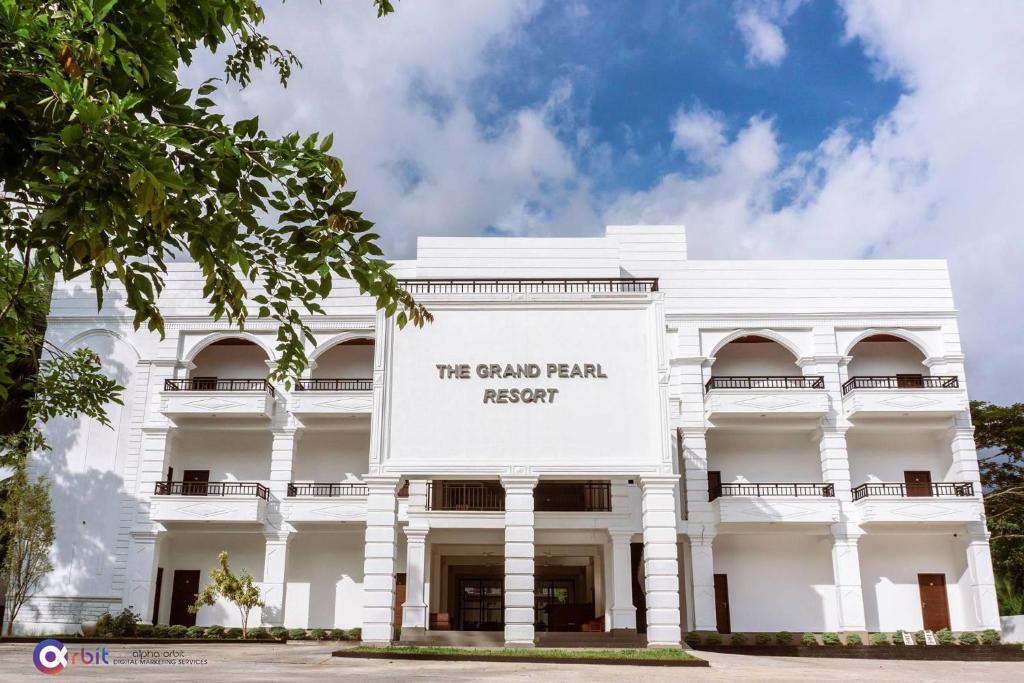 MonaragalaThe Grand Pearl Resort的一座白色的建筑,上面标有读我们大棕榈度假村的标志