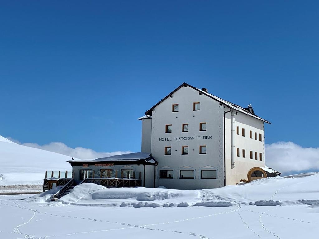 卡纳泽伊库尔拉娜酒店的雪地中的白色建筑,有雪覆盖的地面