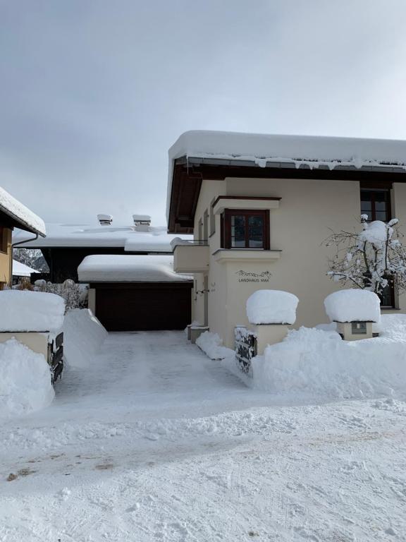 加尔米施-帕滕基兴Landhaus MAX的前面有长凳的雪地房子