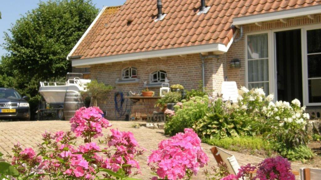 马斯丹B&B de Oude Hofstee的前院有粉红色花的房屋