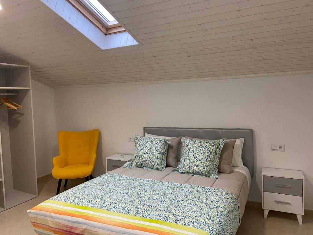 波尔托马林Os Arcos - Apartamentos Turísticos的一间卧室配有一张床和一张黄色椅子