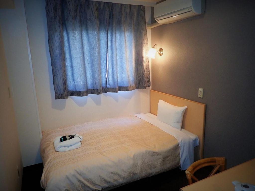 东京Hotel Suntargas Ueno - Vacation STAY 08474v的一间卧室配有一张床,上面有电话