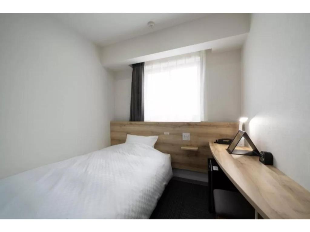 名古屋R&B Hotel Nagoya Shinkansenguchi - Vacation STAY 14999v的一间卧室配有一张床、一张书桌和一个窗户。