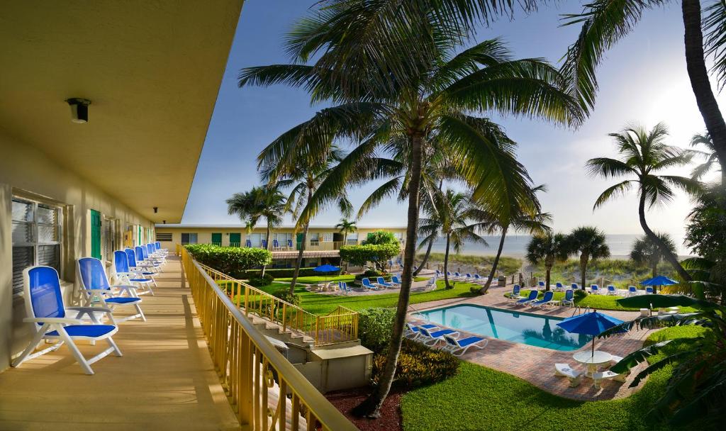 劳德代尔堡Tropic Seas Resort的一个带椅子、游泳池和棕榈树的度假阳台