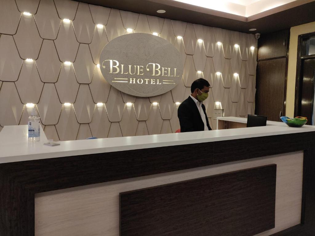 大诺伊达Blue Bell Hotel - Greater Noida的站在蓝色钟楼柜台后面的人