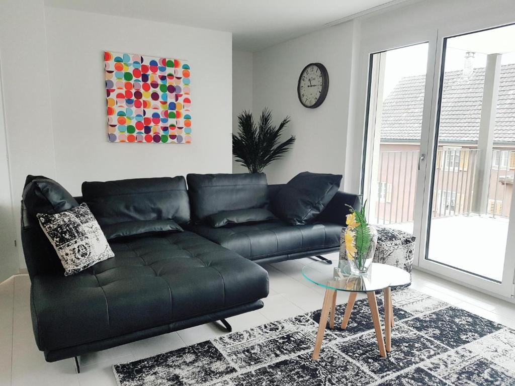 DietwilEasy-Living Apartments Dietwil的客厅配有黑色真皮沙发和桌子
