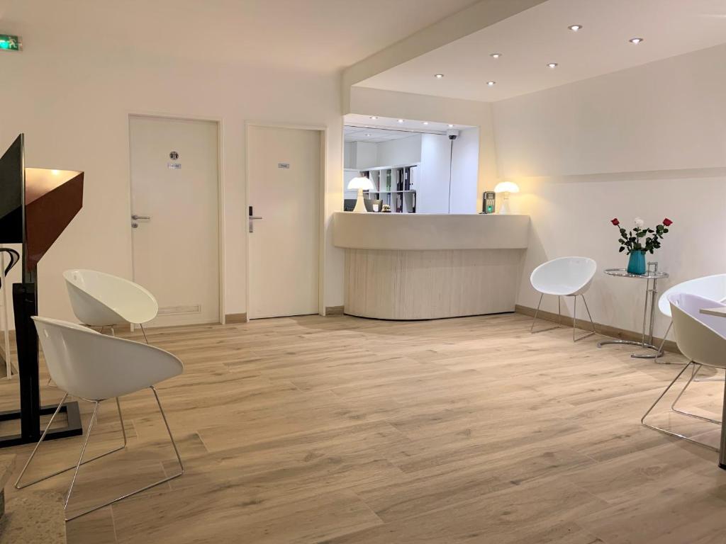 卢森堡法国酒店的一间设有白色椅子和柜台的房间以及一间厨房