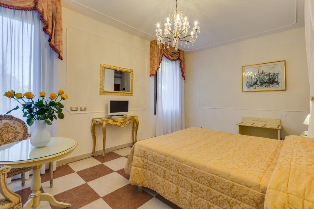 威尼斯Hotel Bernardi Semenzato的一间卧室配有一张床、一张桌子和花瓶