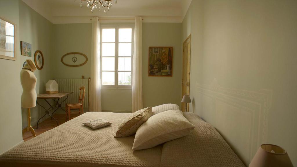 阿尔勒Au coin de la Roquette的卧室配有带枕头的床铺和窗户。