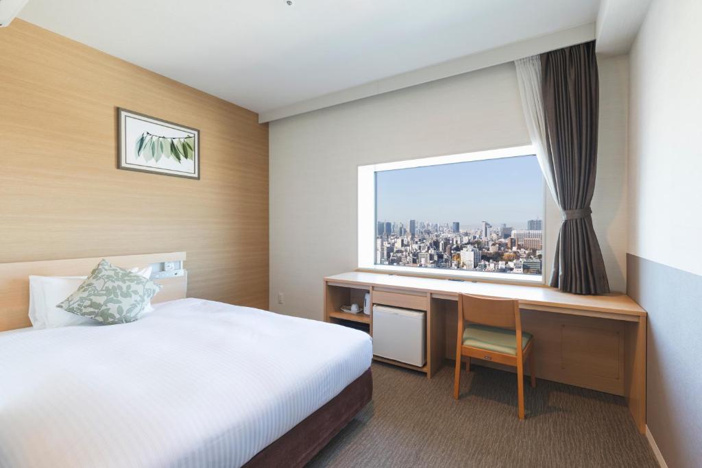 东京Hotel Crown Hills Ueno Premier的配有一张床、一张书桌和一扇窗户的酒店客房