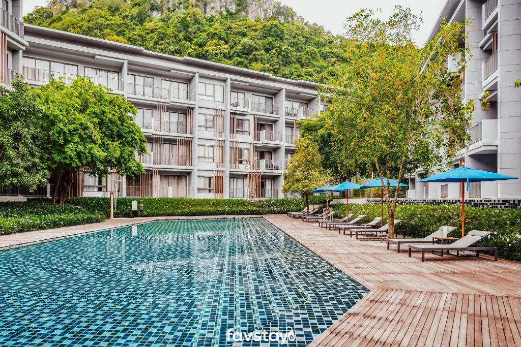 Phayayen23 Degrees Khao Yai by Favstay的大楼前的游泳池配有椅子和遮阳伞