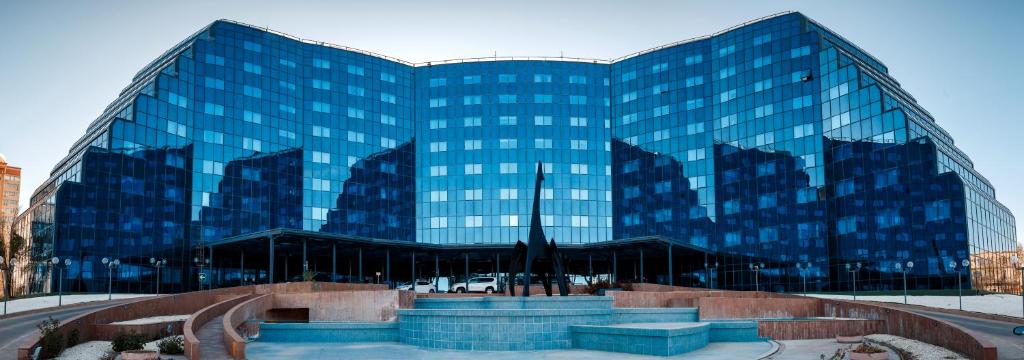 阿特劳滨河宫酒店的一座大型玻璃建筑,前面有一个喷泉