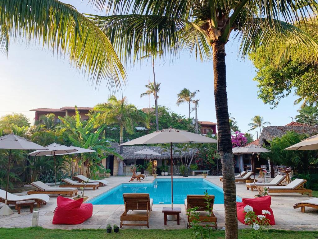卡姆布库Controvento Boutique Hotel的一个带椅子和遮阳伞的游泳池以及棕榈树
