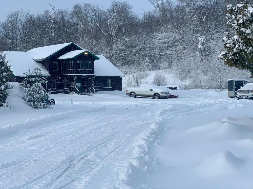 RedfieldTug Hill Resort的车道上汽车被雪覆盖的房子