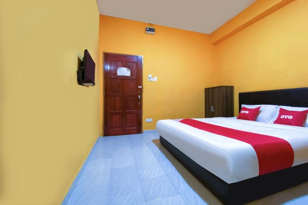 加央Super OYO 90039 Coop Hotel Kangar的一间卧室配有一张带红色和白色枕头的大床