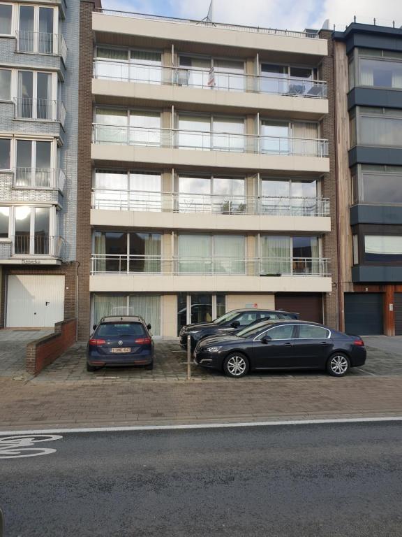 科克赛德Appartement, residentie Syci的两辆汽车停在大楼前的停车场