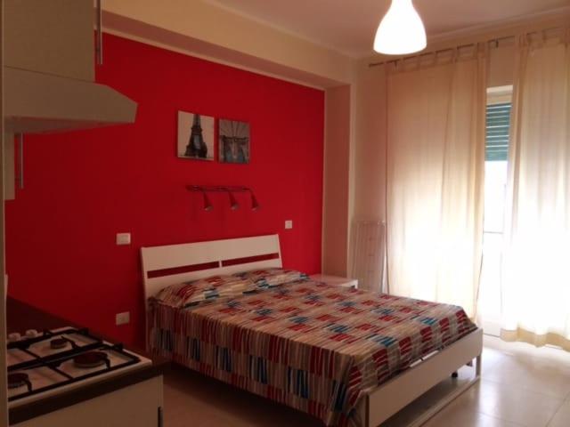 卡坦扎罗Suite La Rosa Dei Venti的红色卧室配有一张床和炉灶