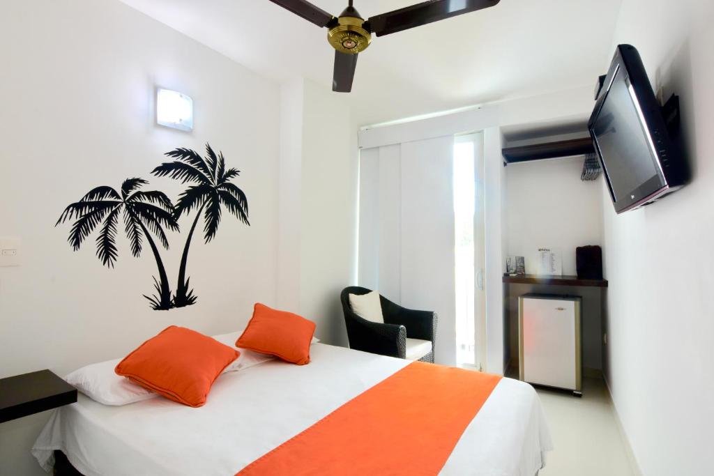 辛塞莱霍Hotel Florida Sincelejo的一间卧室配有带橙色枕头的床和电视。