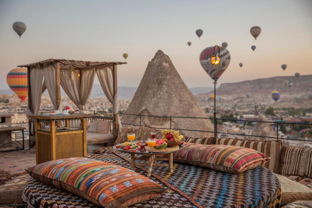 格雷梅迪万岩洞酒店的阳台配有沙发、桌子和热气球