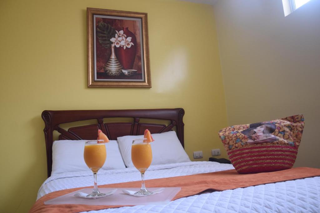 埃斯梅拉达斯Hotel Cayapas Esmeraldas的睡在床上的两杯橙汁