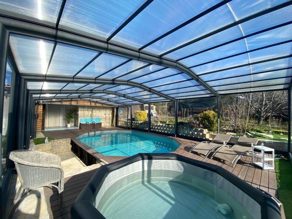 马赛Chambre d hôtes AU CŒUR DES OLIVIERS的一个带游泳池和大型玻璃屋顶的庭院