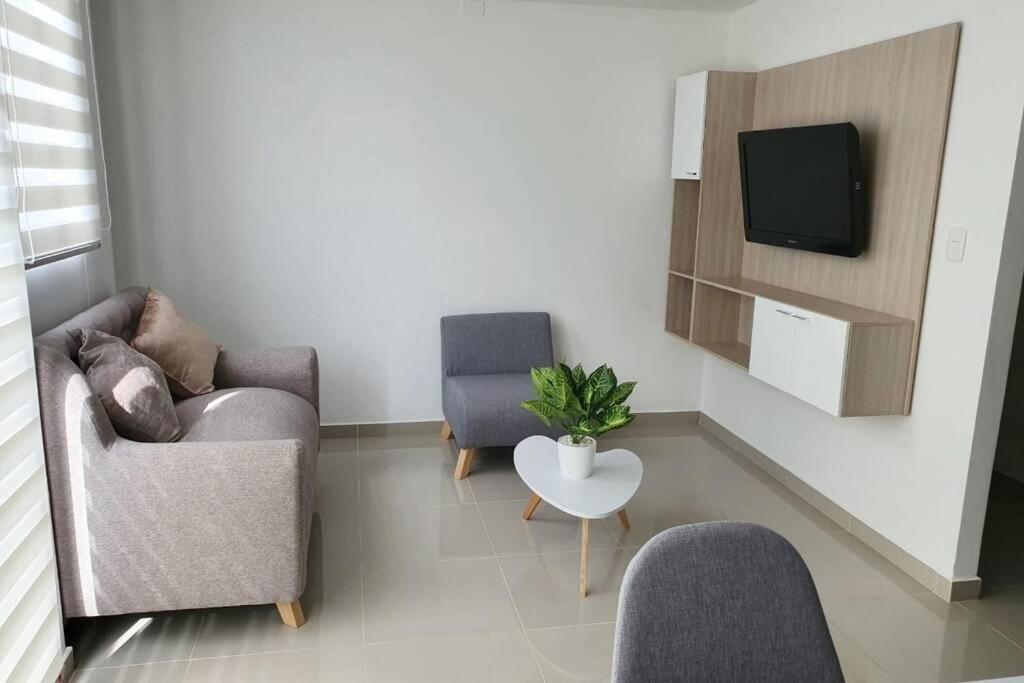 库库塔Apartamento Completo, Perfecto para tus viajes的客厅配有两把椅子和电视