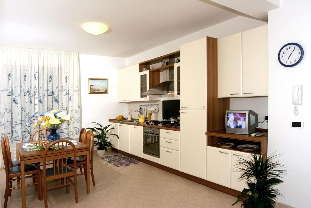 托尔托雷托Verde Mare "Appartamenti per Vacanze"的厨房以及带桌子和时钟的用餐室。