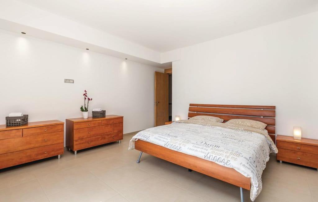 里耶卡Apartman Villa Pećine的一间卧室配有一张大床和两张木制梳妆台。