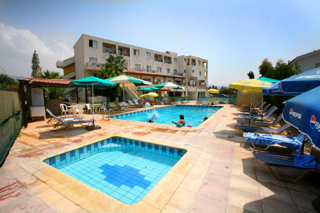 珊瑚湾佩特撒公寓式酒店的一个带椅子和遮阳伞的游泳池以及酒店