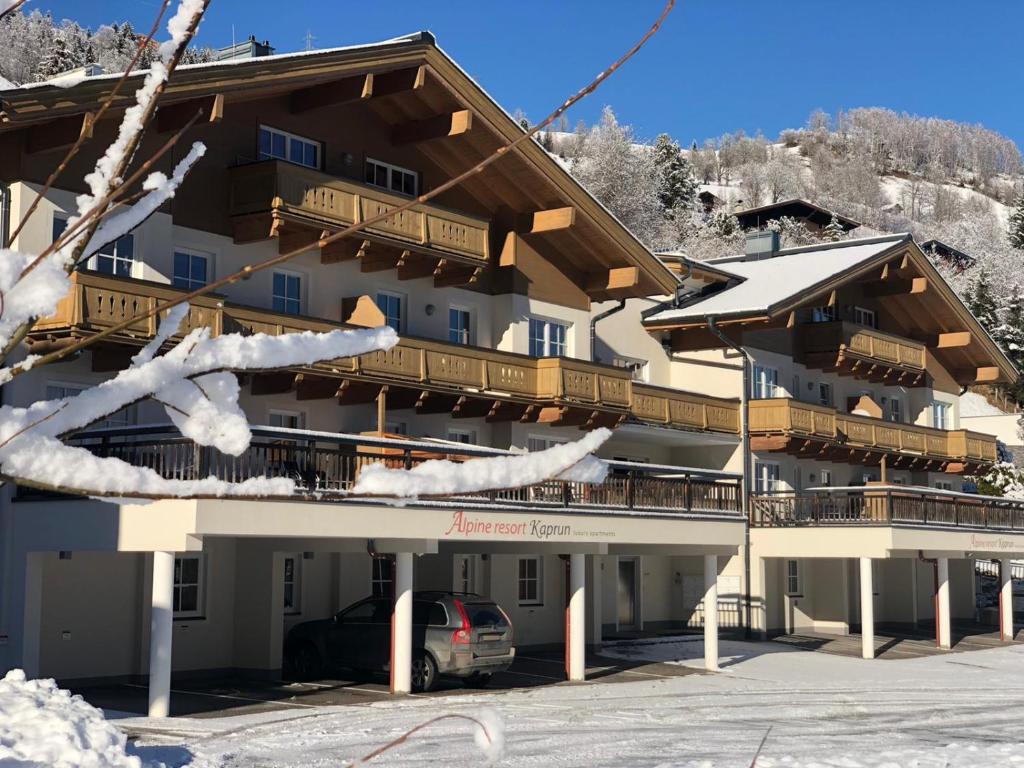 卡普伦AlpinResort Kaprun 2的一座大型建筑,前面有停车位