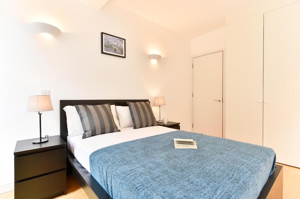 伦敦Shoreditch Vibe Apartments的一间卧室配有一张带蓝色毯子的床