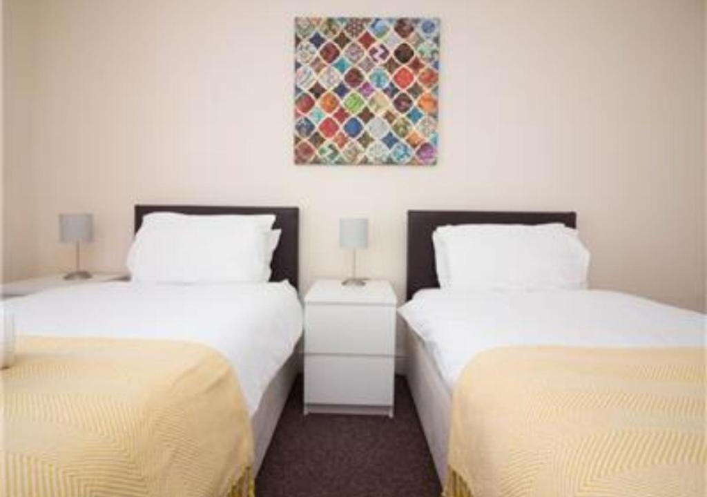 南安普敦StayZo Penthouse Accommodation 2- Premier Lodge的一间设有两张床的客房,墙上挂着一幅画