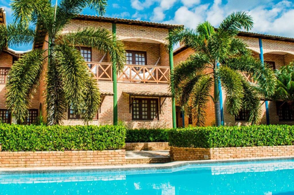 帕拉库鲁Hotel Vento Brasil的游泳池前棕榈树的房子