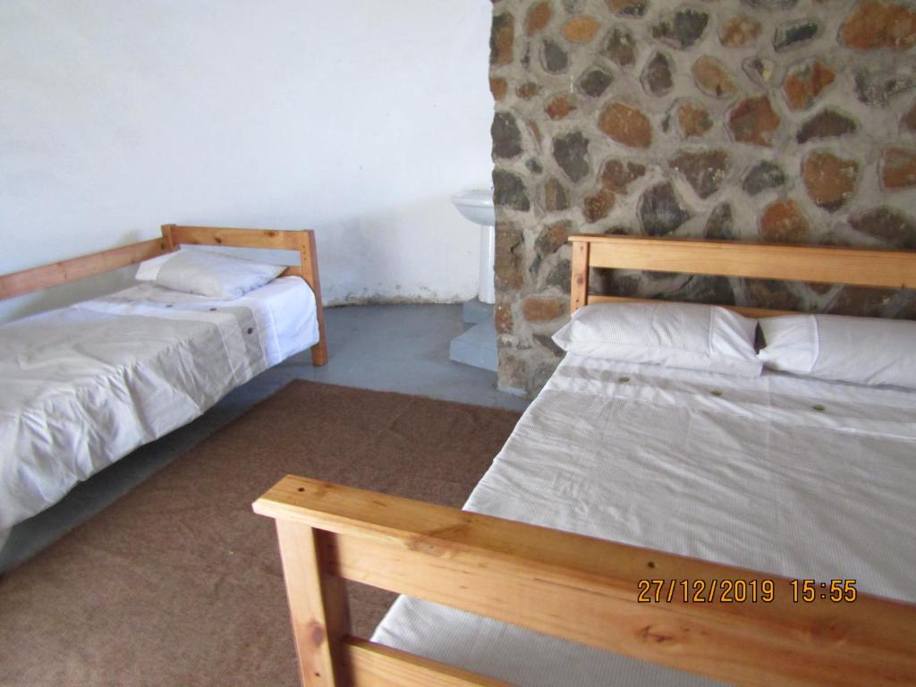 MokhotlongLibibing chalets的石墙客房的两张床