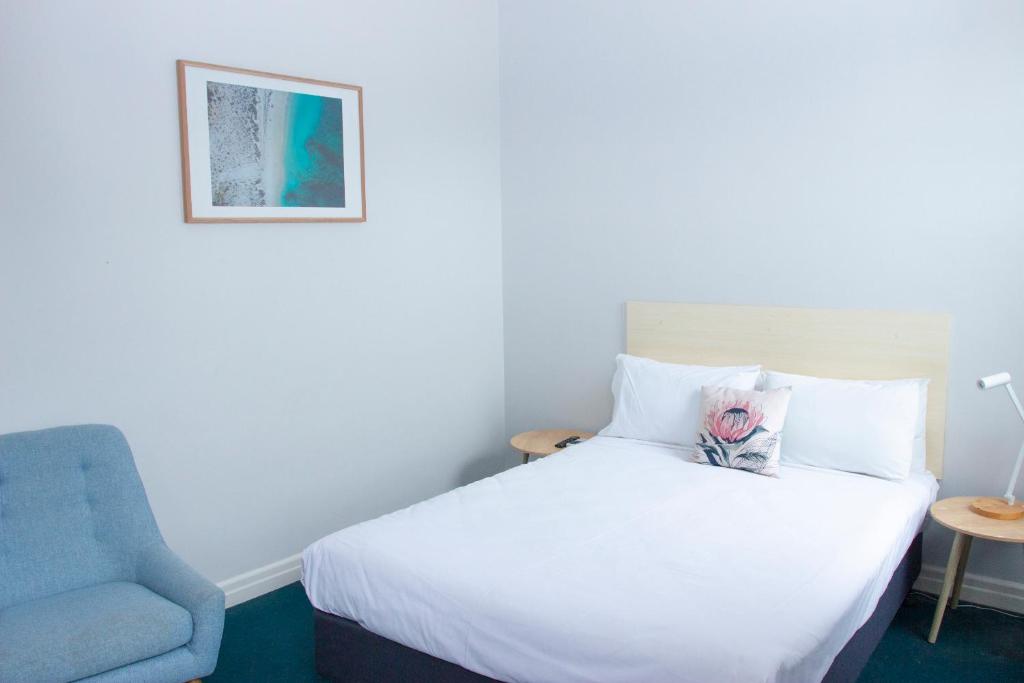 悉尼罗克代尔格兰德酒店的一间卧室配有一张床和一张蓝色椅子