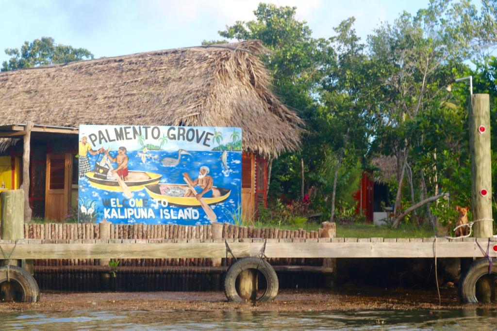 霍普金斯Palmento Grove Garifuna Eco-Cultural & Healing Institute的水面上房子的边的标志