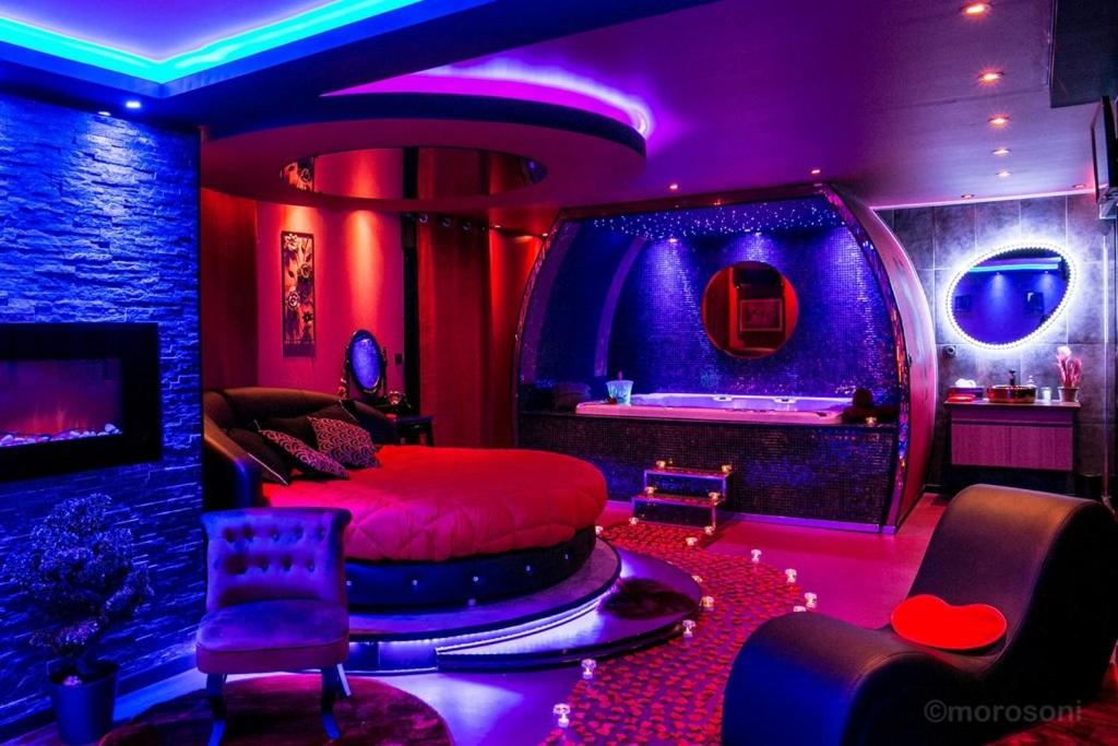 图卢兹L'Insolite Spa Privatif ''Suite Luxueuse-Jacuzzi"的紫色灯室里一间卧室,配有一张床