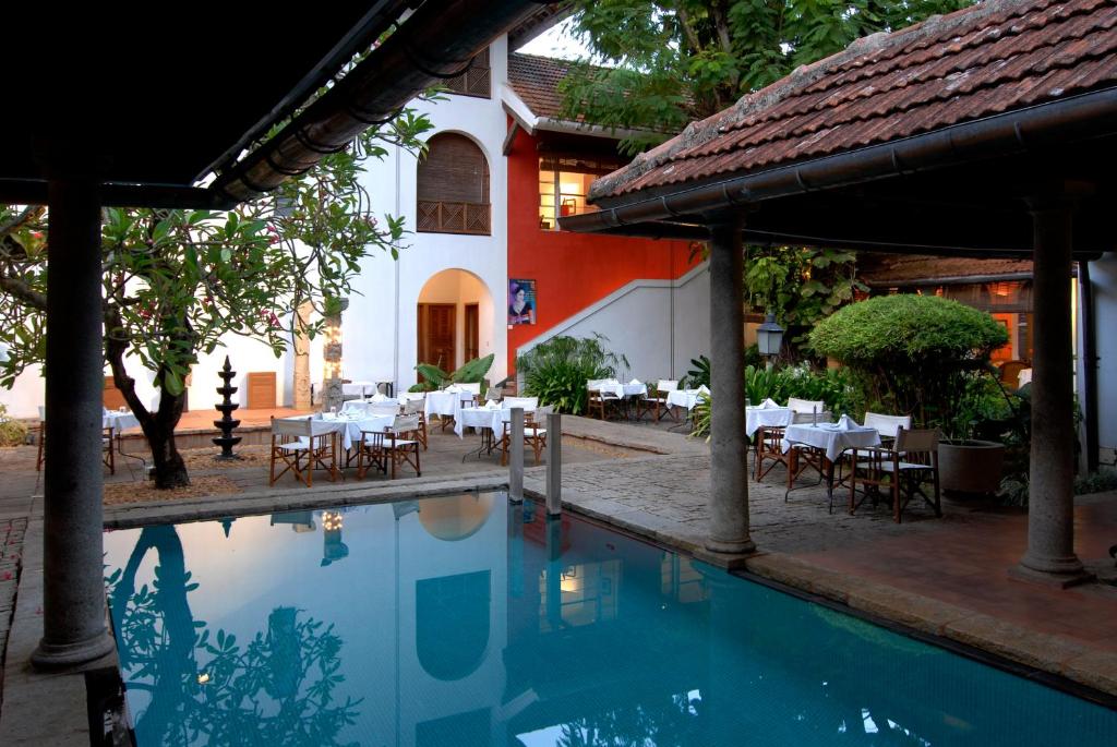 科钦Malabar House的一座带桌椅的游泳池位于大楼旁