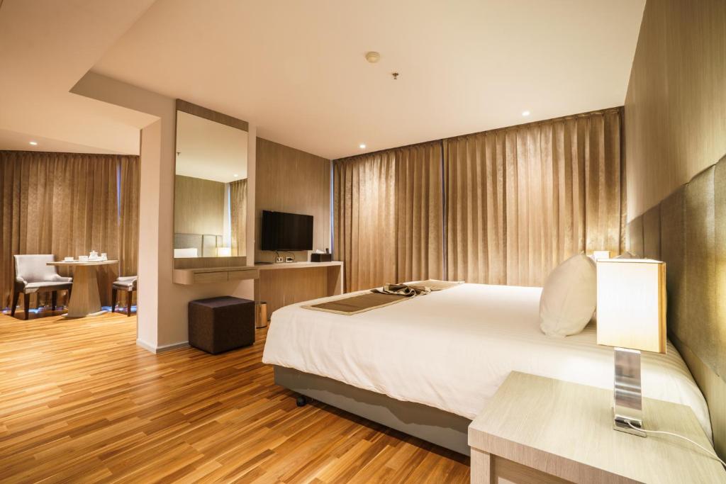 合艾New Season Square Hotel - SHA Plus的酒店客房设有一张大床和一张桌子。