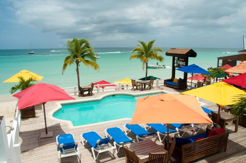 尼格瑞尔棕榈度假村的一个带遮阳伞和椅子的游泳池以及大海