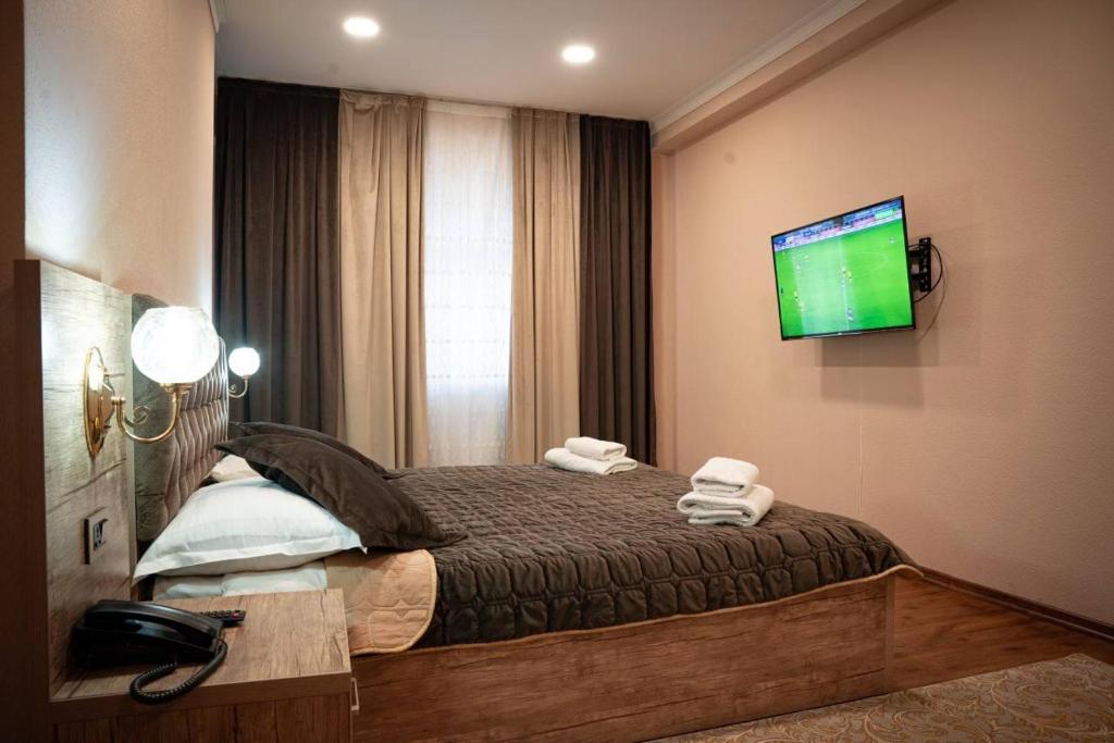 塔什干Dream Inn H&A的卧室配有一张床铺,墙上配有电视
