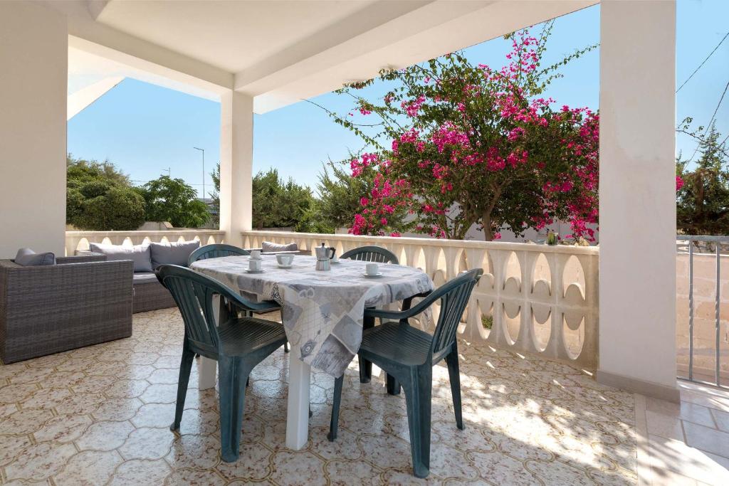 贝瓦尼亚圣彼得Casa Bouganville by BarbarHouse的庭院里摆放着一张桌子和椅子,上面摆放着粉红色的鲜花